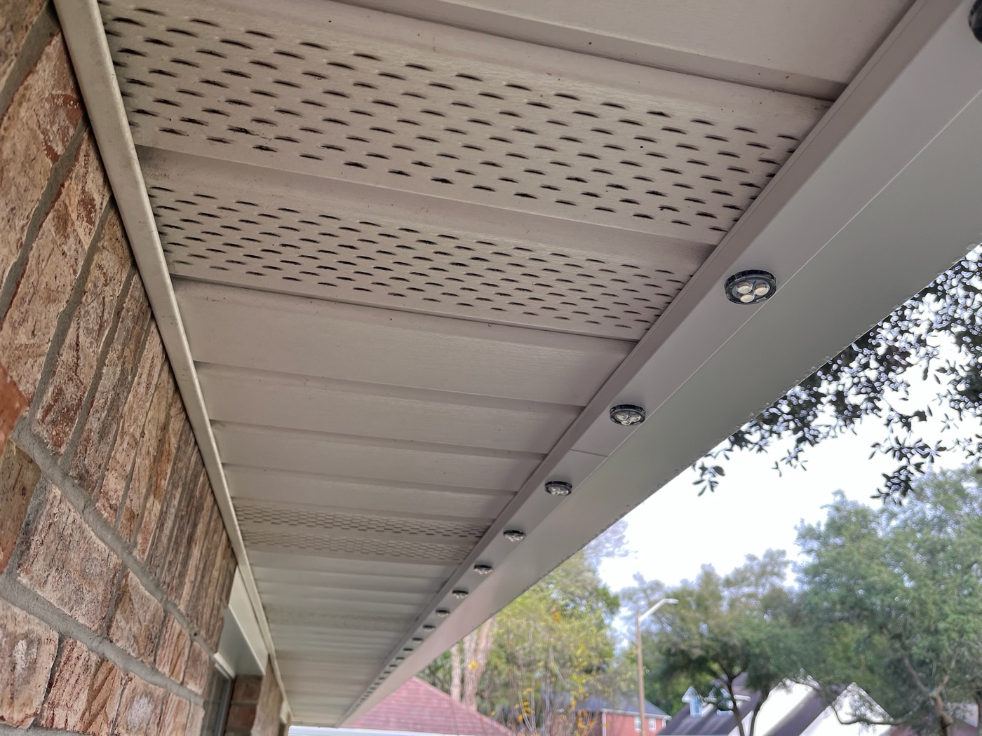 Chameleon puck lights in white aluminum track under a soffit, with no wiring visible.